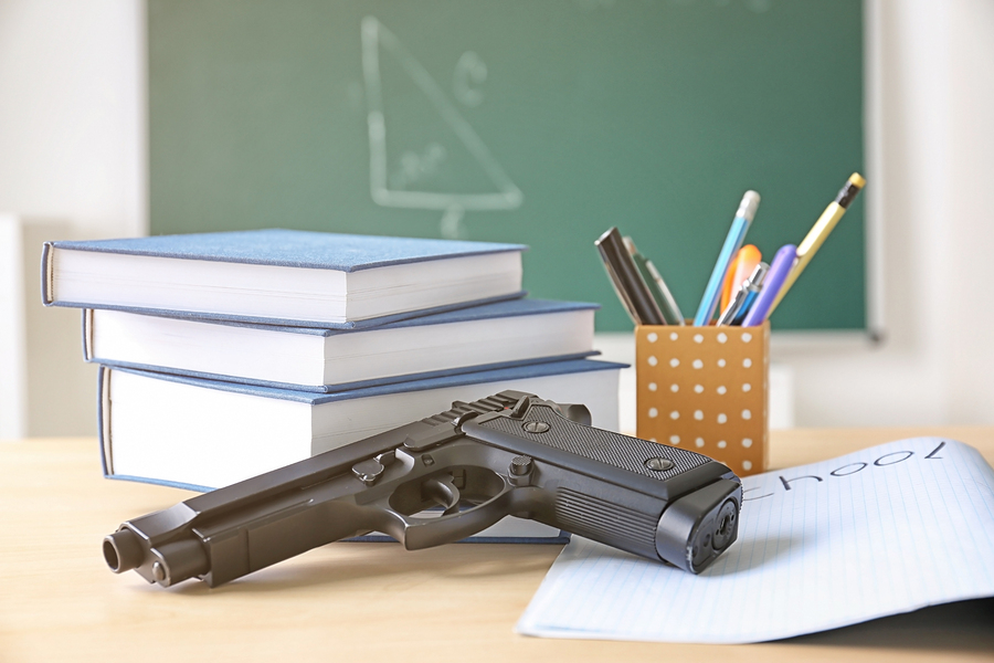 School stationery and gun on table in class School stationery and gun on table in class