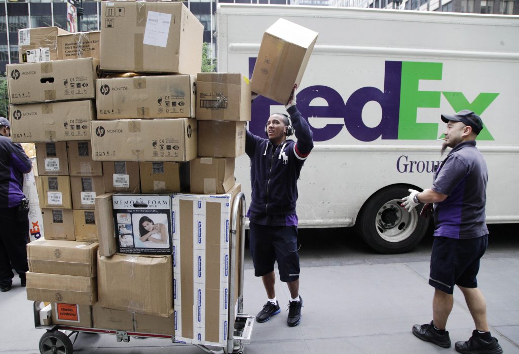 Infrastructure Growing Gridlock New York FedEx workers sort boxes for delivery on a busy street.