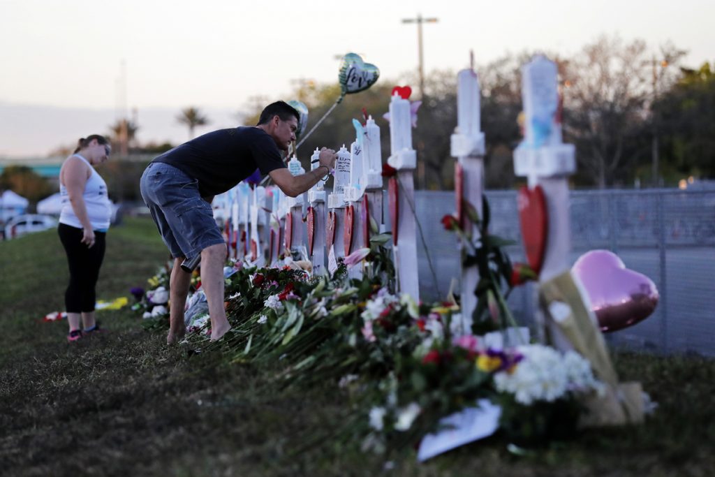 School Shooting Florida Paul Birmingham, on Monday, Feb. 19, 2018, writes on a cross placed in memory of student Gina Montaldo outside of Marjory Stoneman Douglas High School