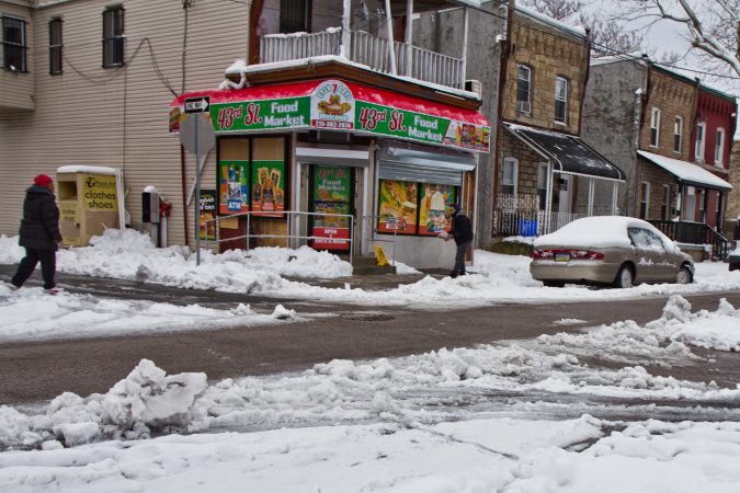 Residents and business owners salt sidewalks Thursday morning in West Philadelphia. (Kimberly Paynter/WHYY)