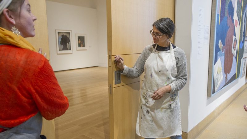 On the last day of the Chuck Close Exhibit, MFA printmaking students Candace Jensen left, and Melissa Joseph close the exhibit doors. MFA students and museum staff then proceeded to cover the doors with protest posters. (Jonathan Wilson for WHYY)