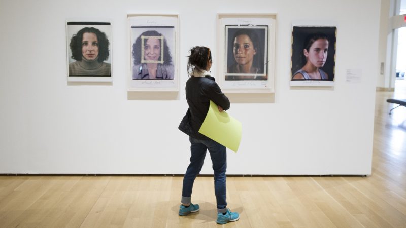 Tamara Weiss carries her protest poster with her as she views the Chuck Close Exhibit. (Jonathan Wilson for WHYY)