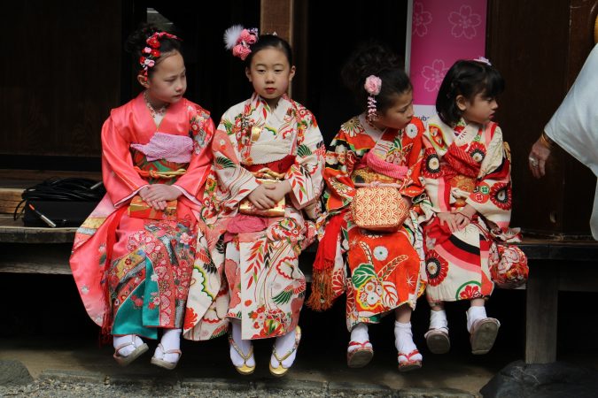 Students from the Japanese Language School of Philadelphia (from left) Julia Epps, 8, Suzu Noda, 8, Julia Casey, 7, and Alyssa Casey, 5, wait to play their part in the opening ceremony for the Cherry Blossom Festival at the Japanese House and Garden in Fairmount Park. (Emma Lee/WHYY)