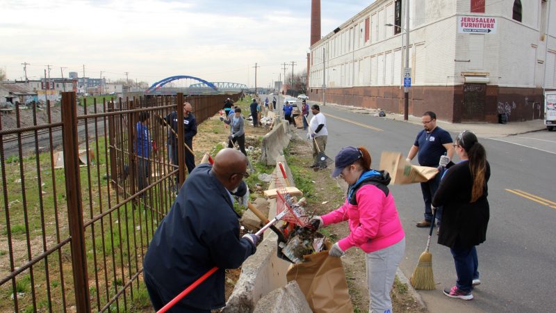 About 30 workers and volunteers clean up trash along Gurney Street near the former site of a notorious heroin encampment. (Emma Lee/WHYY)