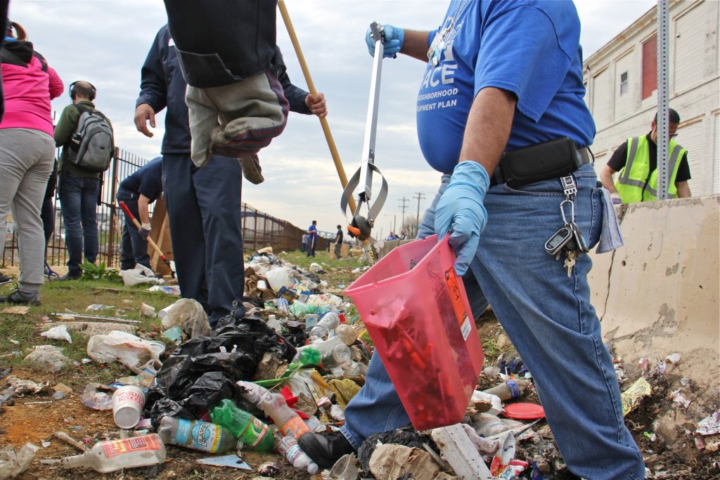 Tony Beltram of HACE separates the syringes from the rest of the trash. Hundreds of used syringes were found during the clean up of the block-long stretch grass between Gurney Street and the Conrail tracks.