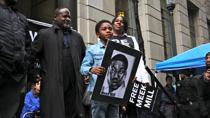 Meek Mill's son, Papi, accompanied by his grandmother, the rapper's mother Kathy Williams, takes the stage during a rally outside the Criminal Justice Center. (Emma Lee/WHYY)