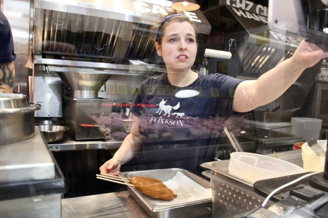 Rebecca Foxman prepares corn dogs at Fox and Son at Reading Terminal Market. (Emma Lee/WHYY)