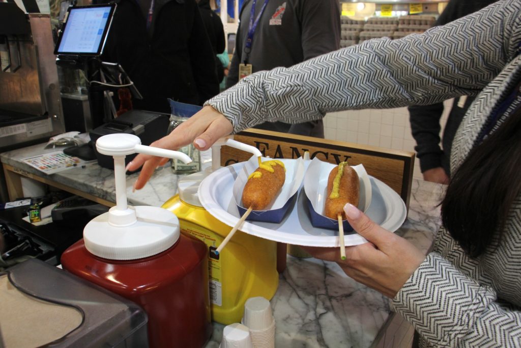 2018 04 19-e lee-reading terminal market-science festival food corn dogs A customer adds mustard to corn dogs at Fox and Son at Reading Terminal Market. (Emma Lee/WHYY)