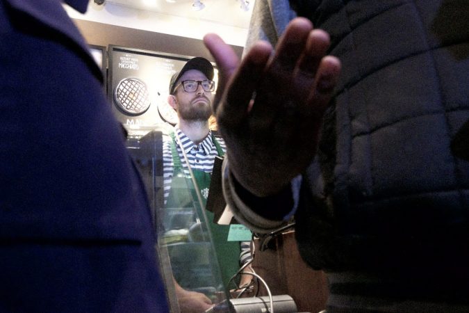 A Starbucks employee looks on as Asa Khalif speaks to people gathered inside a Starbucks on 18th and Spruce streets in Philadelphia to protest Thursday's controversial arrests of two black men. (Bastiaan Slabbers/for WHYY)