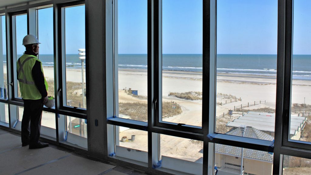 20180425Upstairs-view- Stockton's director of operations; Alex Marino looks out at the Atlantic Ocean. He is standing inside what will be the common area for one of Stockton's four bedroom suites.
(Bill Barlow/for WHYY)