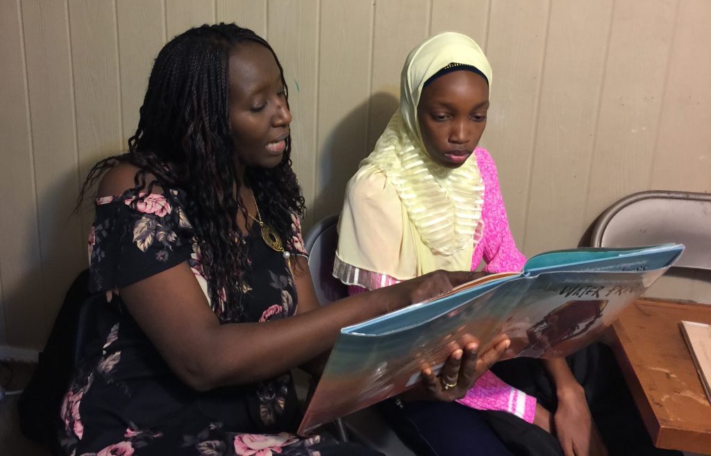 #500EmpoweringAfricanStories (Dieynaba photo) Aminata Sy reading to Dieynaba, an eighth-grader from Senegal who recently came to the U.S. (Photo courtesy of Aminata Sy)