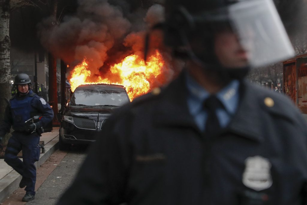 Trump Inauguration Protests A parked limousine burns as riot police clear the street during a demonstration after the inauguration of President Donald Trump, Friday, Jan. 20, 2017, in downtown Washington. Protesters registered their rage against the new president Friday in a chaotic confrontation with police who used pepper spray and stun grenades in a melee just blocks from Donald Trump's inaugural parade route. Scores were arrested for trashing property and attacking officers. (AP Photo/John Minchillo)
