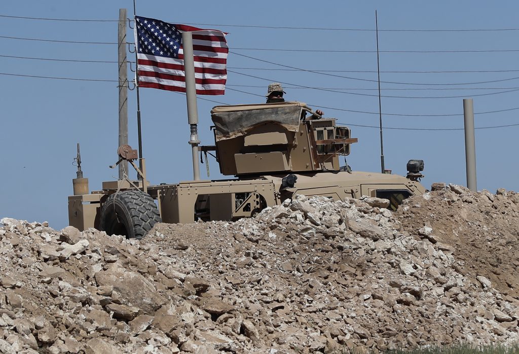 Syria US A U.S. soldier sits on an armored vehicle behind a sand barrier at a newly installed position near the tense front line between the U.S-backed Syrian Manbij Military Council and the Turkish-backed fighters, in Manbij, north Syria, Wednesday, April 4, 2018. A week ago, there was just a single house where U.S. soldiers had hoisted a U.S. flag on a hill a little ways back from a tense front line in Syria. Now on Wednesday stood a growing outpost with a perimeter of large sand barriers and barbed wire, a new watch tower and half a dozen armored vehicles, The Associated Press found. (Hussein Malla/AP Photo)