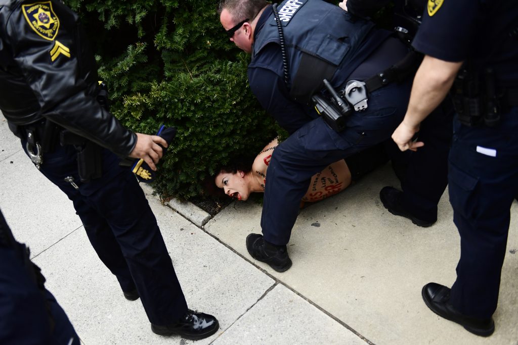 A protester is detained as Bill Cosby arrives for his sexual assault trial at the Montgomery County Courthouse, Monday, April 9, 2018, in Norristown, Pa.