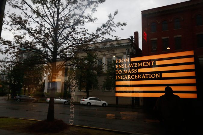 A man inside the Justice and the Legacy Museum is reflected on the front door, as an outside view is seen through the door in Montgomery, Ala., Sunday, April 22, 2018. The combined museum and a new memorial planned to open Thursday will be the nation's first site to document racial inequality in America from slavery through Jim Crow to the issues of today, said the nonprofit Equal Justice Initiative, a legal advocacy group in Montgomery. (Brynn Anderson/AP Photo)