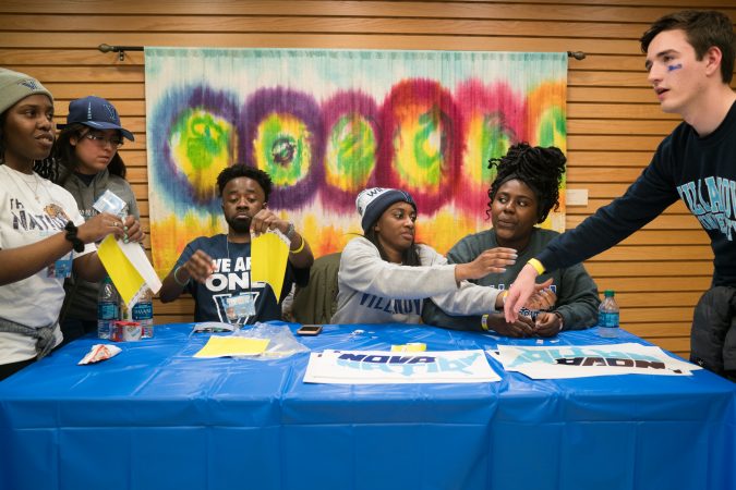 Villanova students Opeyemi Famakinwa, Nkiambi Sokolo, Takiyah Bethea and Ijeoma Ezengwa pass out wristbands to fellow students at the Connelly Center before the NCAA men's basketball championship game. (Branden Eastwood for WHYY)