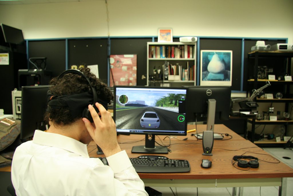 Brian Smith puts on a pair of headphones to play his racing game. He made a user interface so blind players can drive in video games just like sighted players.