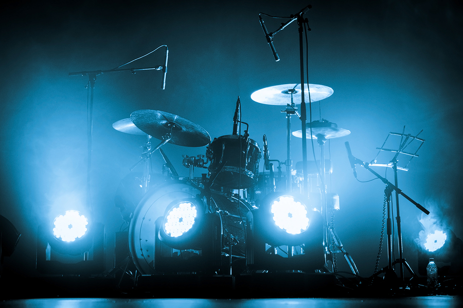 bigstock–219255136 A kit of drums and a microphones on an empty stage in blue smoke before the concert