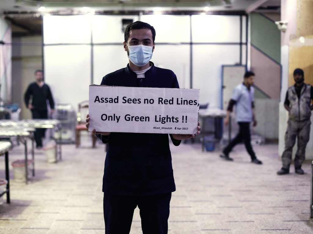 A medical worker at a Damascus hospital holds a sign protesting a suspected chemical weapons attack outside the Syrian capital a year ago. The suspected attacks led the U.S. to fire a barrage of missiles at a Syrian air base on April 7, 2017. A medical worker at a Damascus hospital holds a sign protesting a suspected chemical weapons attack outside the Syrian capital a year ago. The suspected attacks led the U.S. to fire a barrage of missiles at a Syrian air base on April 7, 2017. (Sameer Al-Doumy/AFP/Getty Images)