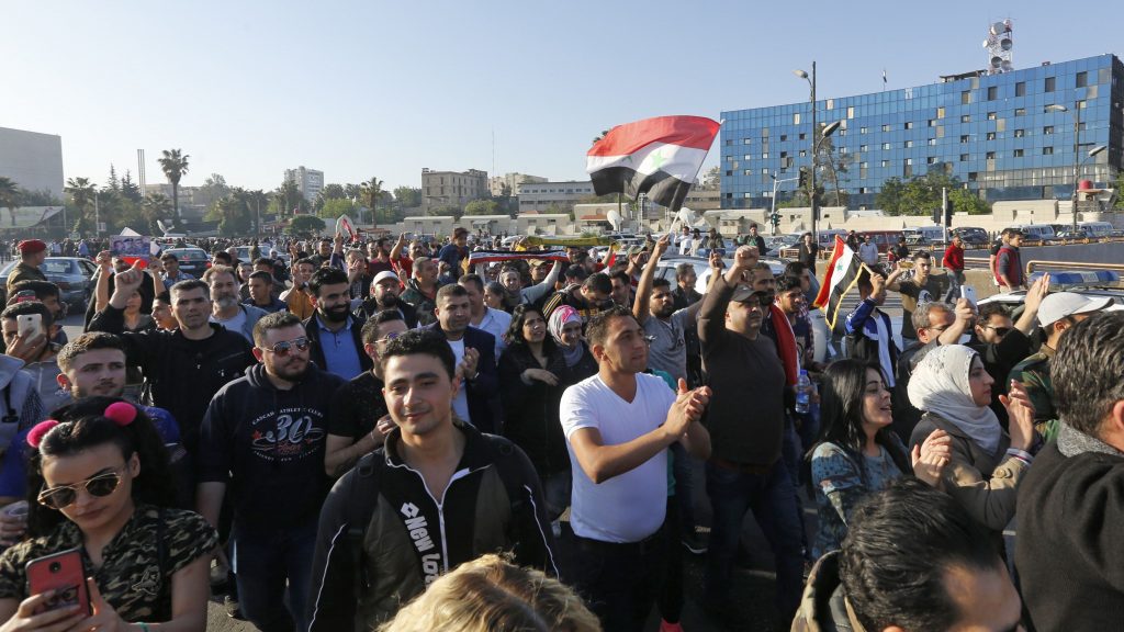 Syrians wave the national flag and portraits of President Bashar Assad as they gather at the Omayyad Square in Damascus on Saturday to condemn the U.S.-led airstrikes. Syrians wave the national flag and portraits of President Bashar Assad as they gather at the Omayyad Square in Damascus on Saturday to condemn the U.S.-led airstrikes. (Louai Beshara/AFP/Getty Images)