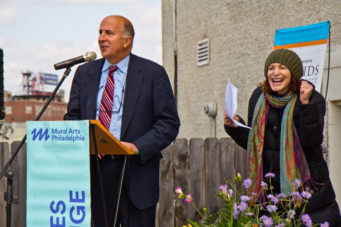 City Councilman Mark Squilla speaks at the dedication of a new mural on top of the Children’s Crisis Treatment Center on Delaware Avenue in Philadelphia. Mural Arts’ executive director Jane Golden celebrates. (Kimberly Paynter/WHYY)