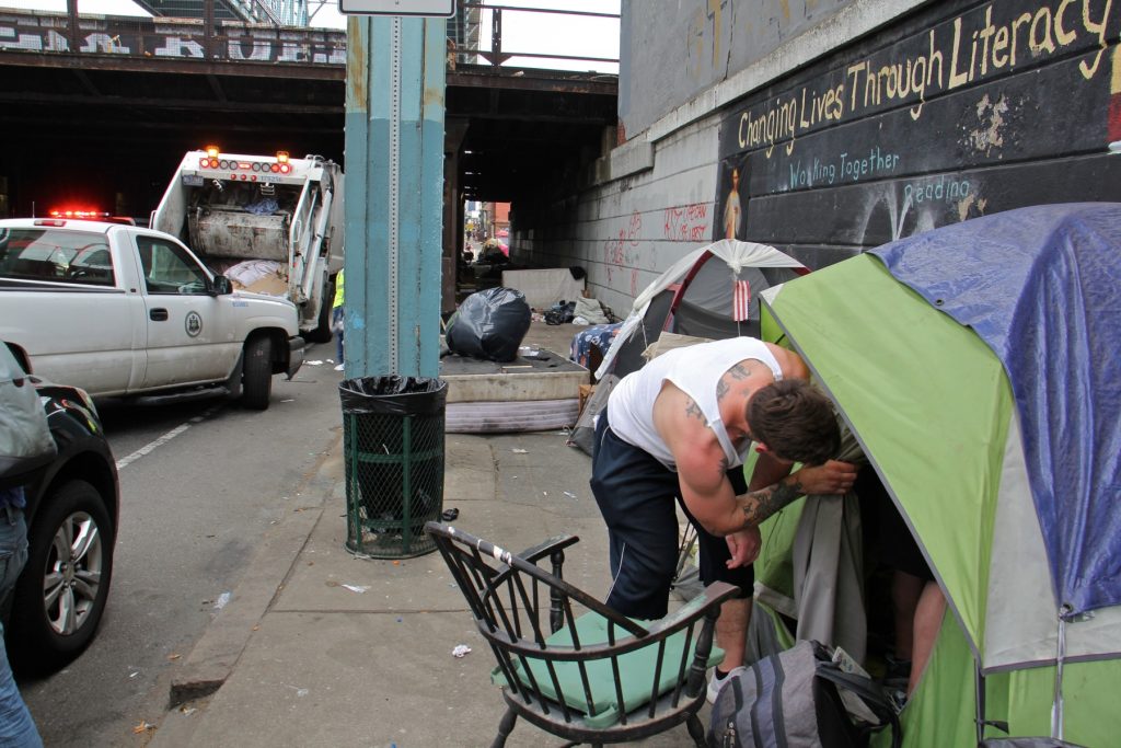 A visitor to the Kensington Avenue heroin encampment checks on a friend. (Emma Lee/WHYY)