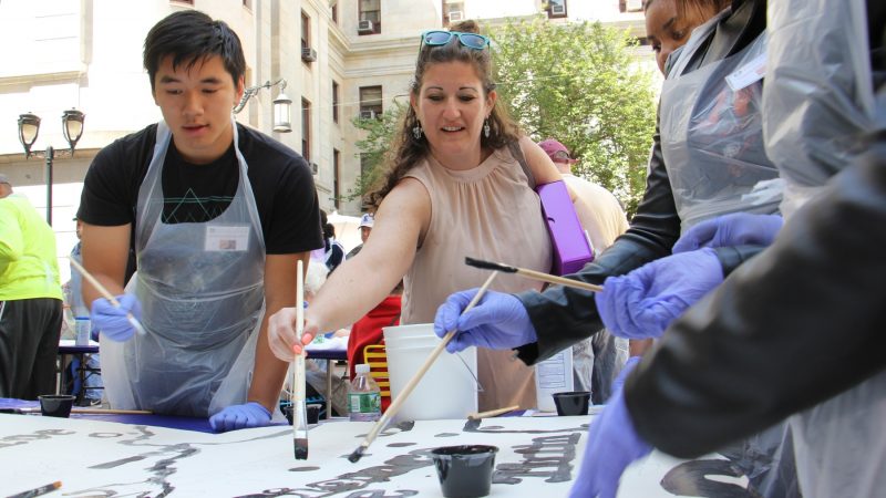 Dunbar school teacher Mindy Fisher helps students to paint the Octavius Catto mural. (Emma Lee/WHYY)