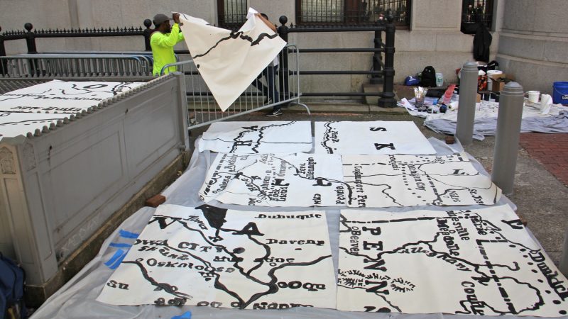 Mural Arts workers lay out painted pieces of the Octavius Catto mural. (Emma Lee/WHYY)