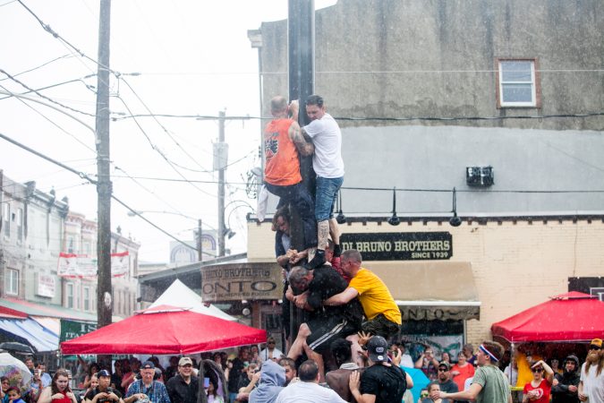As a heavy rain started to fall the South Philly team who has competed in past years tries to climb the grease pole anyway. (Brad Larrison for WHYY)