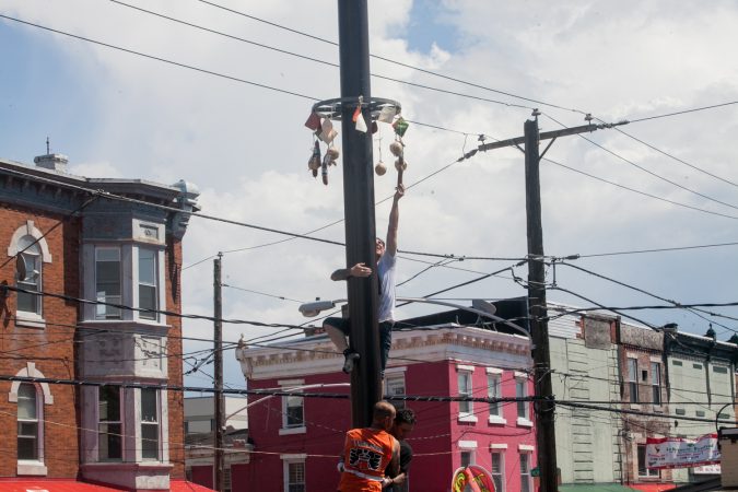 Nick Cordisio climbs on to his teammates shoulders and grabs a piece of cured meat that hung from the top of the grease pole. (Brad Larrison for WHYY)
