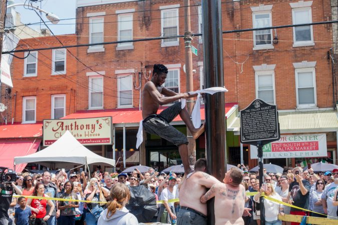 Tyler Dallas of South Philadelphia attempts to ascend the grease pole at the Italian Market Festival Sunday. (Brad Larrison for WHYY)