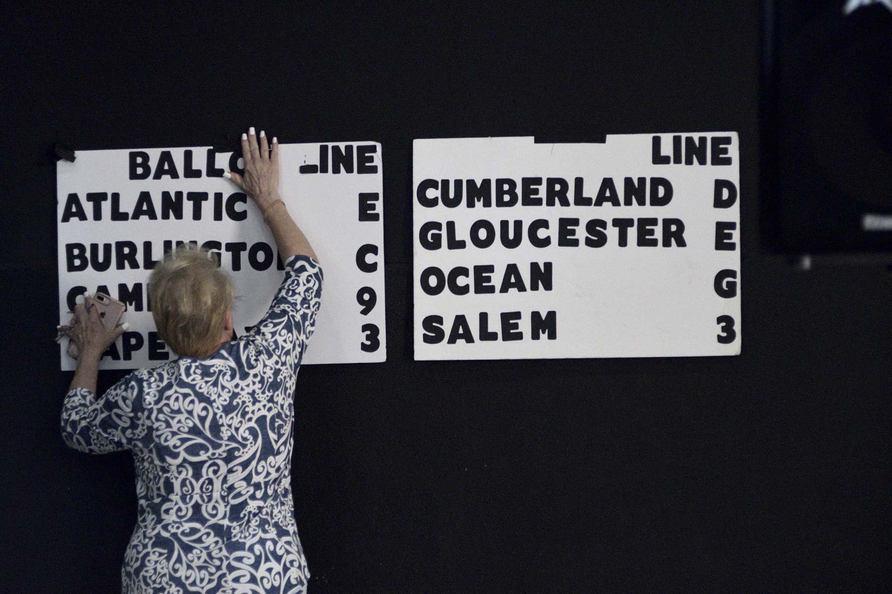 Campaign volunteer Helen Duda mounts a board indicating the candidate's position on the eight different ballots for the upcoming congressional primaries.