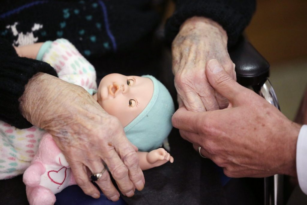 AP Poll Long Term Care In this April 14, 2016, file photo, a son, (at right), holds his mother's hand at her nursing home in Michigan. Most young adults haven’t given much thought to their own needs as they get older, but a significant number are already providing long-term care for older loved ones, according to a new poll by the Associated Press-NORC Center for Public Affairs Research. (Carlos Osorio/AP Photo, File)
