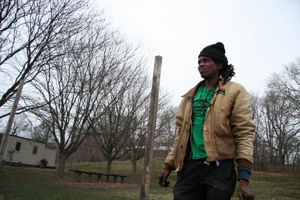 Chris Bolden-Newsome stands and looks out at the Sankofa Community farm. He farms using natural farming techniques passed on to him from his parents and grandparents. (Alan Yu/WHYY)