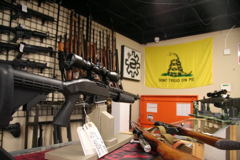 A display of rifles in a gun shop, with a flag that says 