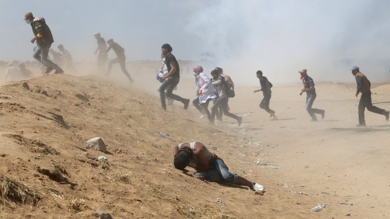 Palestinian demonstrators run or take cover from tear gas fired by Israeli forces at the Israel-Gaza border. (Ibraheem Abu Mustafa/Reuters)