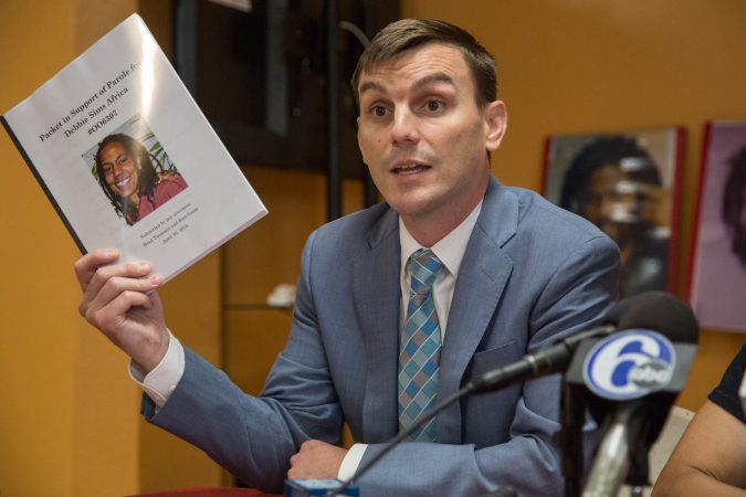 Brad Thomson, a Chicago-based lawyer, holds up the thick packet of letters of support for Debbie Africa's that were presented to the parole board. (Emily Cohen for WHYY)