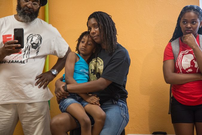 Robin Africa holds her daughter, Alia, 6, at the first public appearance of Debbie Africa since being released from prison after 39 years and 10 months. (Emily Cohen for WHYY)