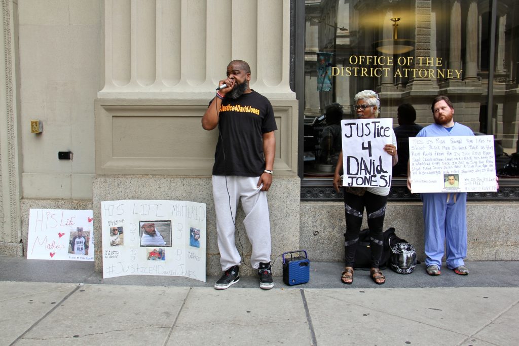 2018 06 08-e lee-isaac gardner-philadelphia district attorney-justice for david jones Isaac Gardner (left), of the Justice for David Jones Coalition, leads a small protest outside the district attorney's office calling for charges against Ryan Pownall, the Philadelphia police officer who fatally shot Jones during a traffic stop.