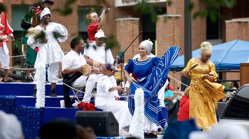 Peaches Jones (in blue dress), smiles atop the Kulu Mele float as it rolls past the viewing area at Independence Mall, during the annual Juneteenth Parade, on Saturday. (Bastiaan Slabbers for WHYY)