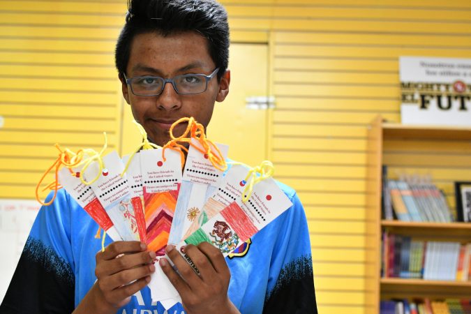 Robert, 14, holds up bookmarks representing the flags of Argentina, Spain, Panama, Colombia, and other countries, at Mighty Writers El Futuro in South Philadelphia. (Bastiaan Slabbers for WHYY)