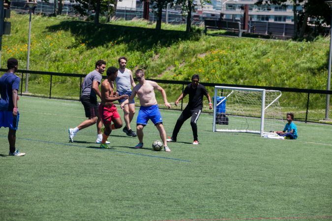 On a picture-perfect day,  players use their lunch break for a game of pickup soccer in Philadelphia's Penn Park. (Brad Larrison for WHYY)