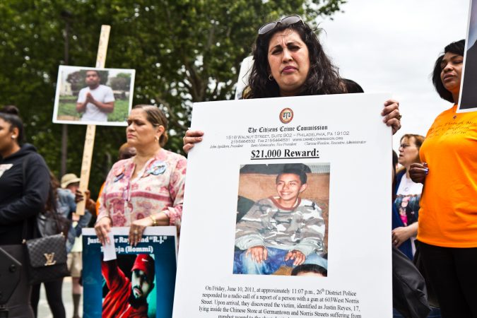 Kathy Lees hold up a sign in remembrance of 17-year-old Justin Reyes, who lost his life to gun violence in 2011. (Kimberly Paynter/WHYY)
