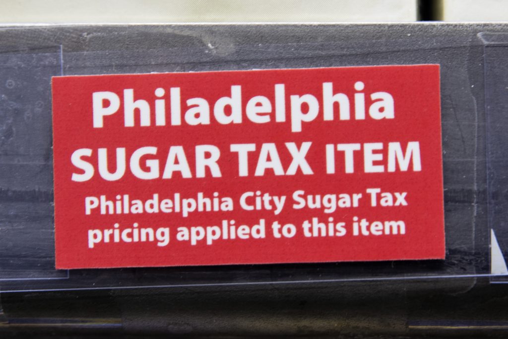 Soda Tax Philadelphia This March 16, 2017 photo shows a sticker alerting customers of the sugar tax posted by sweetened beverages at the IGA supermarket in the Port Richmond neighborhood of Philadelphia.