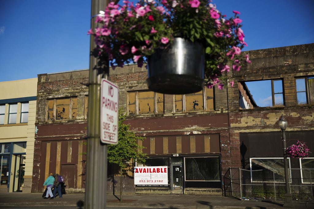 Struggling in a Strong Economy In this June 16, 2017, file photo, dilapidated storefronts stand along baskets of pink petunias that hang from light posts all over town, watered regularly by residents trying to make their city feel alive again in Aberdeen, Wash. From drivers paying more for gas and families bearing heavier child care costs to workers still awaiting decent pay raises to couples struggling to afford a home, people throughout the economy are straining to succeed despite the economy’s gains. (AP Photo/David Goldman, File)