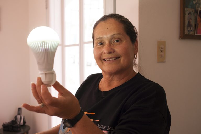 Minerva Ortolaza holds a rechargeable bulb her sister, Santa, uses to light her house. The Ortolazas didn't have light for months after Hurricane Maria hit Puerto Rico and they had to change their routines to make do. (Irina Zhorov/WHYY)