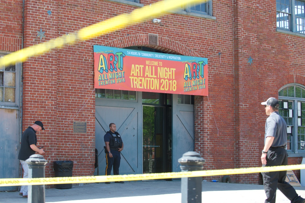 Piserchio_TrentonShooting2 A police officer stands guard outside of the Historic Roebling Wire Works building on S. Clinton Avenue in Trenton, N.J. following a shooting at an all-night arts festival being held there. (Natalie Piserchio for WHYY)