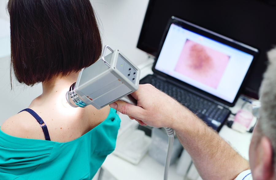 bigstock–213876019 The doctor examines neoplasms or moles on the patient's skin. (Kalinovskiy/Bigstock)