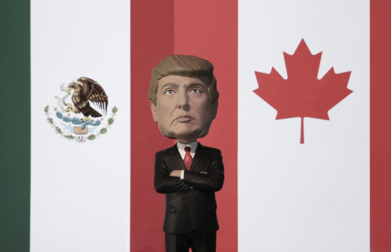 Bobble Head caricature of United States president Donald Trump standing between the flags of Mexico and Canada - NAFTA concept - North American Free Trade Agreement