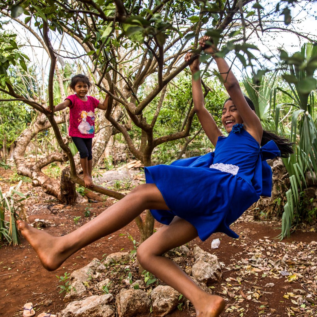 Gelmy, 9, and sister Alexa, 4, climbing trees in the backyard of their family home in the Yucatan Peninsula. Gelmy, 9, and sister Alexa, 4, climbing trees in the backyard of their family home in the Yucatan Peninsula. (Adriana Zehbrauskas for NPR)